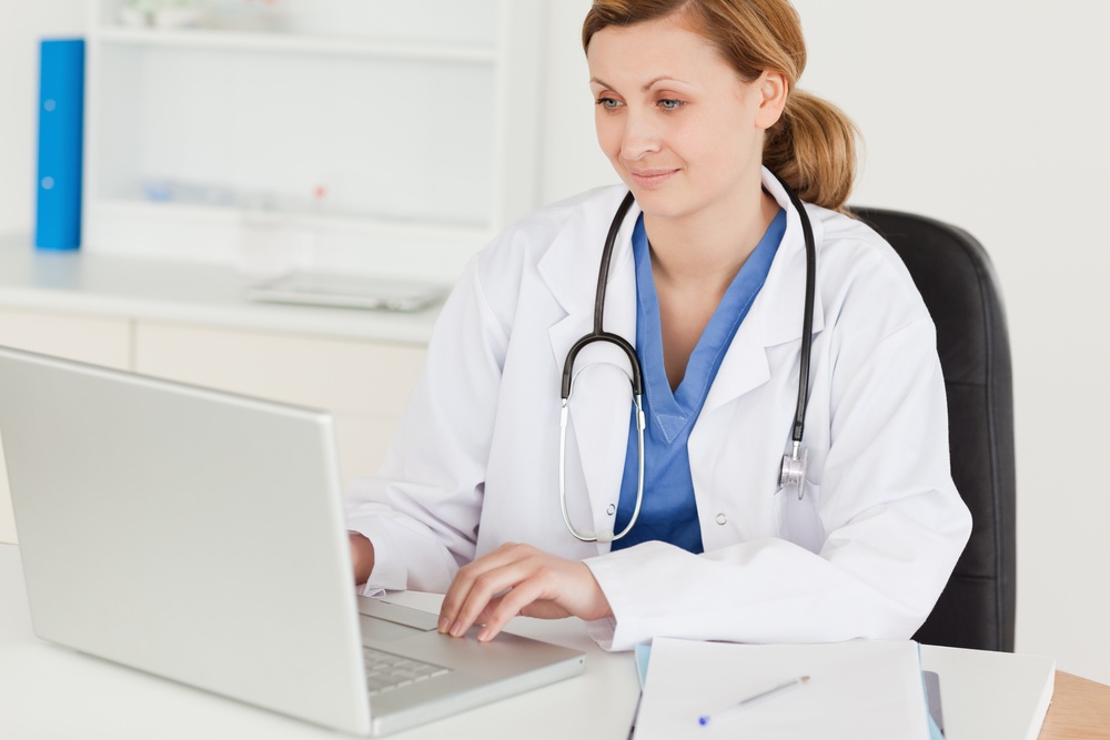 Attractive female doctor working on her laptop in her office